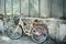 Yellow bicycle is standing in garden, against background of an old brick building. Ð¡oncept of loss, loneliness.