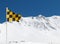 Yellow and black avalanche risk warning flag flying in the mount