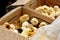 Yellow and black little broiler chickens with down on the body sit in a cardboard box close-up top view. newborn chicks