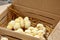 Yellow and black little broiler chickens with down on the body sit in a cardboard box close-up top view. newborn chicks