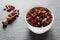 Yellow and black raisins and dried red cranberry in white bowl, wooden scoop on stone background