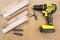 Yellow-black screwdriver on wood background, screws, a set of bits.