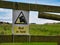 A yellow and black sign fixed to a wooden fence warns walkers of a bull loose in a field ahead