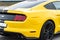 Yellow with black stripes Ford Mustang muscle car in a parking lot. Rear wing view