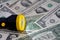 A yellow and black torch with a led light on a blurred background of American money banknote bills currency, USA dollars