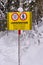 Yellow black warning sign and signs in German, English, Italian and French: Closed, Danger of avalanche. Snow-covered forest