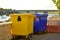 Yellow and blue garbage bin stand on the embankment in the city.