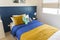 Yellow and blue graphic print pillow setting in teen bedroom.