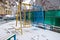 Yellow and blue kids swing covered with white snow