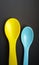 Yellow and blue plastic spoons isolated over black background. Little spoons for feeding babies and toddlers.