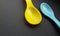 Yellow and blue plastic spoons isolated over black background. Little spoons for feeding babies and toddlers.