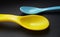 Yellow and blue plastic spoons isolated over black background. Little spoons for feeding babies and toddlers.