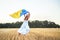 Yellow blue Ukrainian flag in hands of girl running on mangled field of wheat. Happy child with the flag of Ukraine. Independence