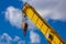 Yellow boom of a loading crane against a blue sky with clouds