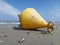 A yellow bouy brought to shore by the sea