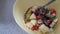 yellow bowl with yogurt apple kiwi granola and chia seed on grey rock table