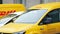 Yellow branded vehicles with red DHL logo. Courier delivery service automobile