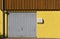 Yellow brick wall with garage door, mail box, downspout and wooden paneling on the second floor