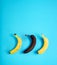 Yellow and brown banana shape on bright blue background. Minimal fashion, flatlay