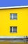 Yellow building wall with two windows with metal grills