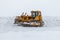 Yellow bulldozer removes snowdrifts in a severe blizzard at winter