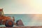 Yellow bulldozer rides on the beach. In the background sea and sky. Light from the right side. Copy space