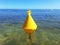 Yellow buoy floating in turquoise water of the caribbean sea under tropical blue sky. Navigation, signaling and maritime safety in