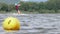 A yellow buoy is floats on a surface in a lake with a surfer