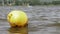 A yellow buoy is floats on a surface in a lake with a surfer on a background