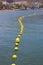 Yellow buoys strung together like pearls to provide a safety exclusion barrier for an area used by boats and pleasure craft