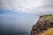 Yellow burnt grass, limestone cliffs covered with green moss on Spanish coast of Bay of Biscay, calm waters of Cantabrian Sea