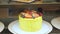 Yellow cake with fresh berries and cream in bakery showcase on glass shelf.