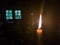 A yellow candle with a long flame in the altar of an Orthodox church near the throne with a menorah opposite the window