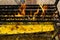 Yellow candles burning on black metal holder with orange flame and yellow candle tears underneath in a Buddhist temple.