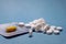 Yellow capsule pills in a blister and white round pills in bulk on a blue background