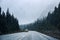 Yellow car driving in heavy snowfall on highway road in pine forest