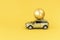 Yellow car model with golden Christmas ball on a yellow background. Concept coming Christmas or Xmas and New year