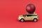 Yellow car model with red Christmas ball on red background. Concept coming Christmas or Xmas and New year