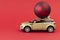 Yellow car model with red Christmas ball on red background. Concept coming Christmas or Xmas and New year. Christmas is coming