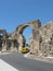 Yellow car passes under the ancient arch