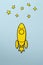 Yellow cartoon rocket flying through space over a blue background