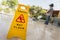 Yellow caution sign and blur of man doing floor polishing