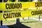 Yellow caution tape in english and spanish barring access to playground equipment at a park.