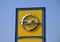 Yellow and chrome color OPEL logo on street sign. blue sky background.