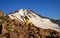 Yellow climbing helmet and red ice axe, lying on a rock in the mountains