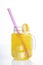 Yellow cocktail in a jar with a handle with half a lemon and a purple straw, isolated on a white background. Refreshing drink