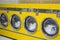 Yellow coin washing machines with laundry in it