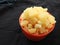 Yellow color Jaggery Slices or cut Pieces in a sand Plastic bowl and Plastic cup isolated on black background