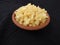 Yellow color Jaggery Slices or cut Pieces in a sand Plastic bowl and Plastic cup isolated on black background