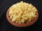 Yellow color Jaggery Slices or cut Pieces in a sand Plastic bowl and Plastic cup isolated on black background